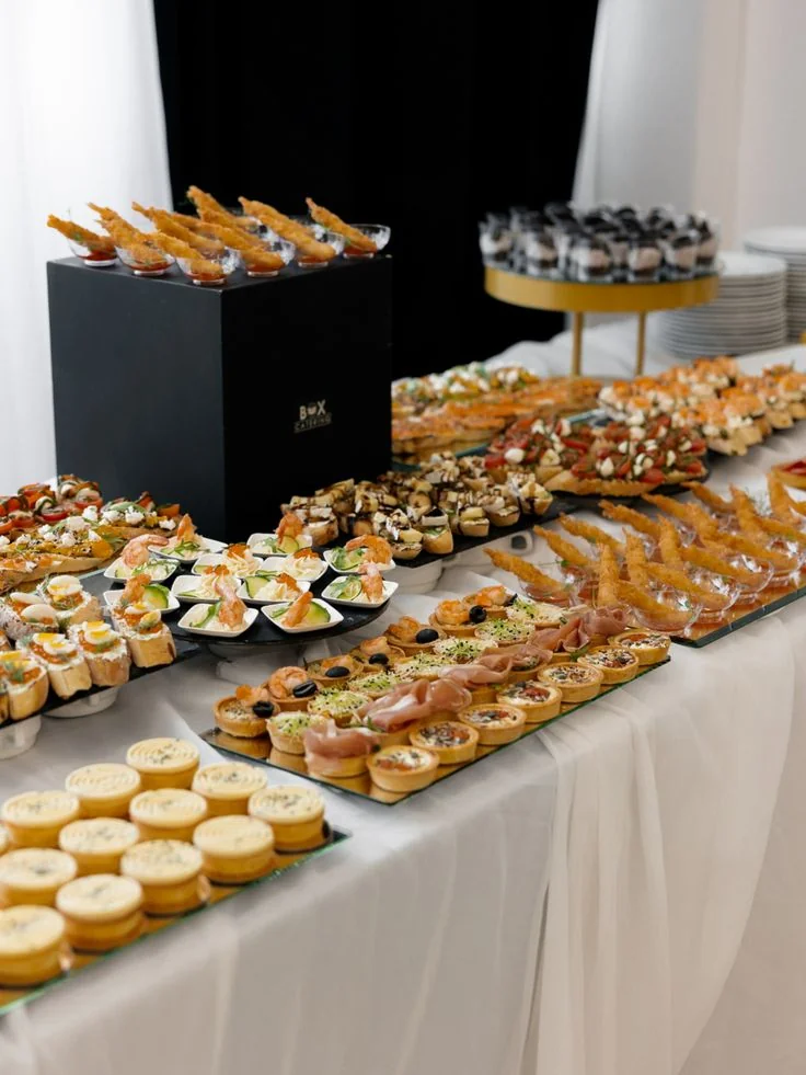 A buffet table set with tartlets, skewers and desserts